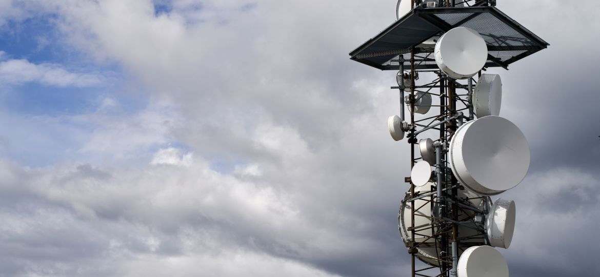 Telecommunications towers against cloudy sky background